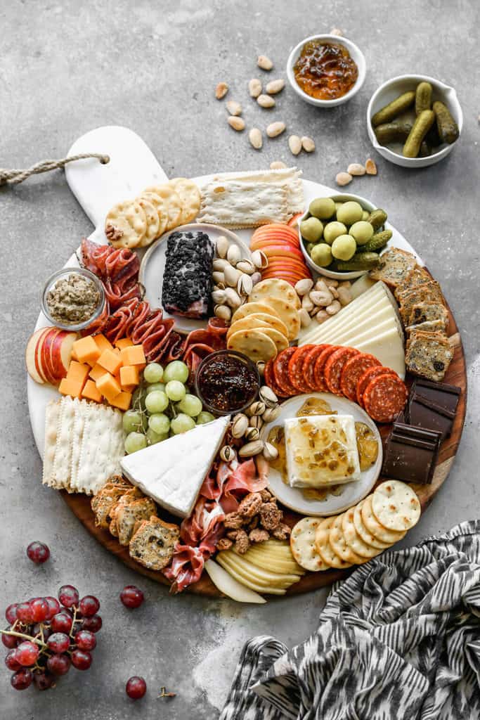 Charcuterie board filled with crackers, meats, nuts and cheese.