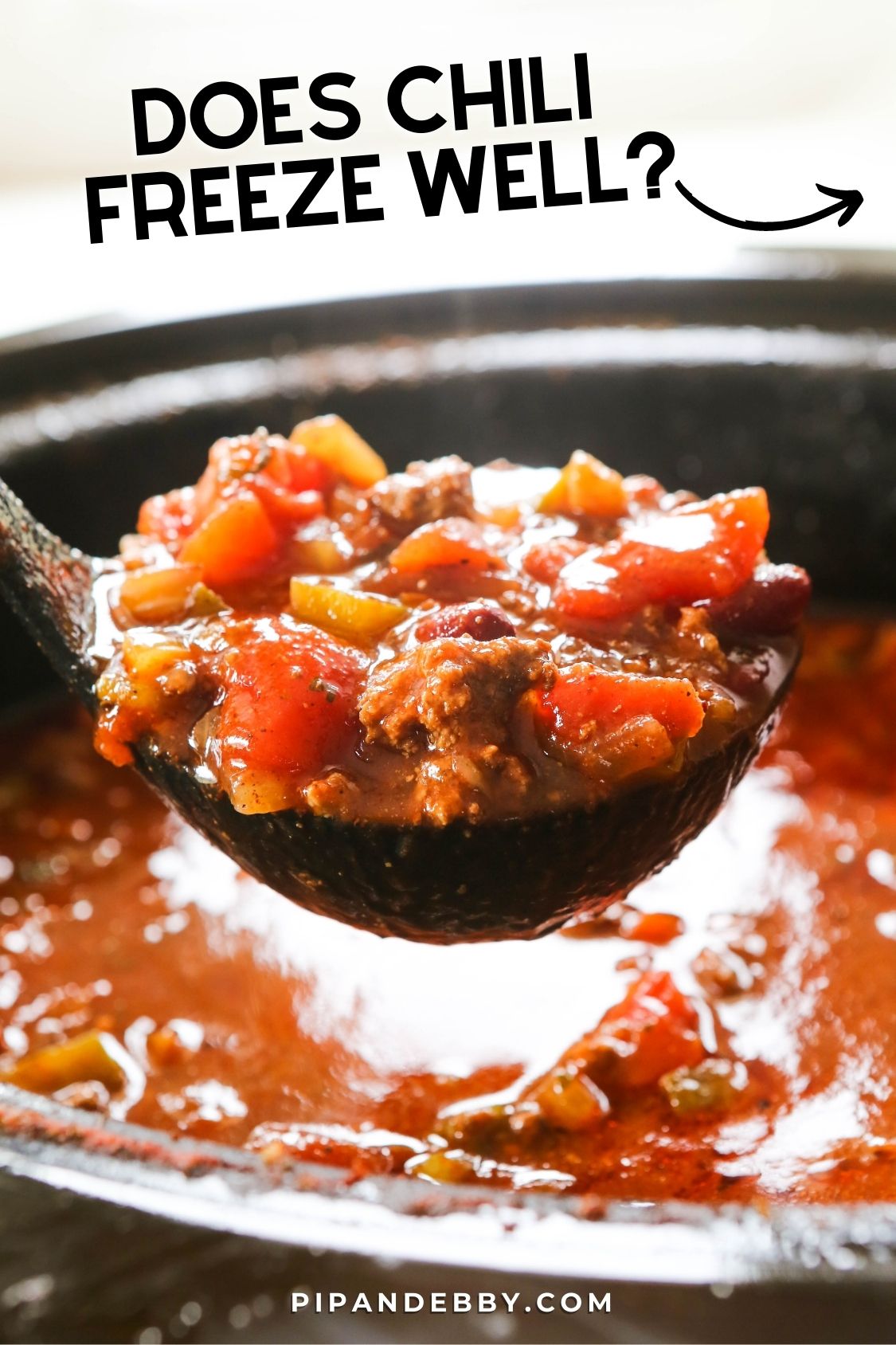 Ladle scooping chili from a slow cooker with text overlay reading, "Does chili freeze well?"