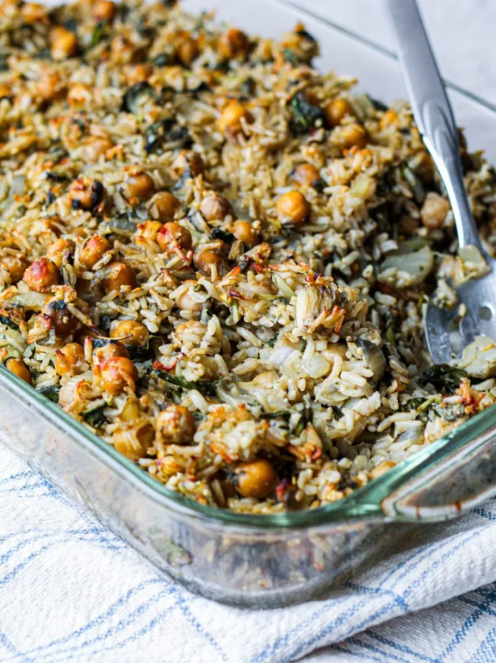 Baking dish of chick pea brown rice spinach artichoke casserole. 