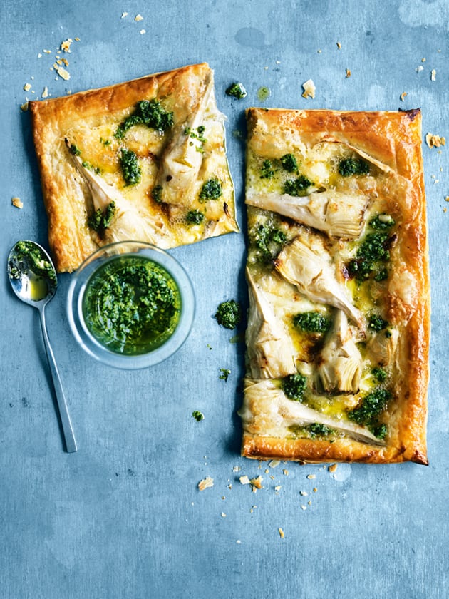 artichoke pesto and brie tarts with a small bowl of pesto next to them. 
