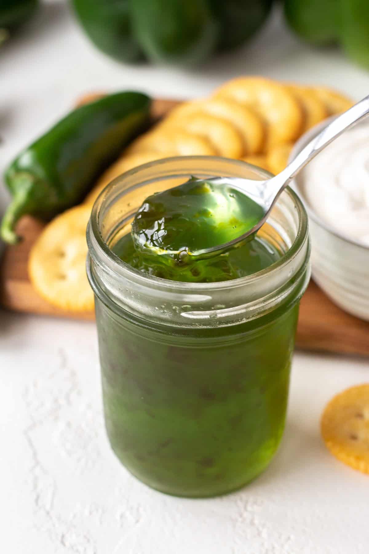 Close-up of vibrant green pepper jelly in a jar with a spoon.