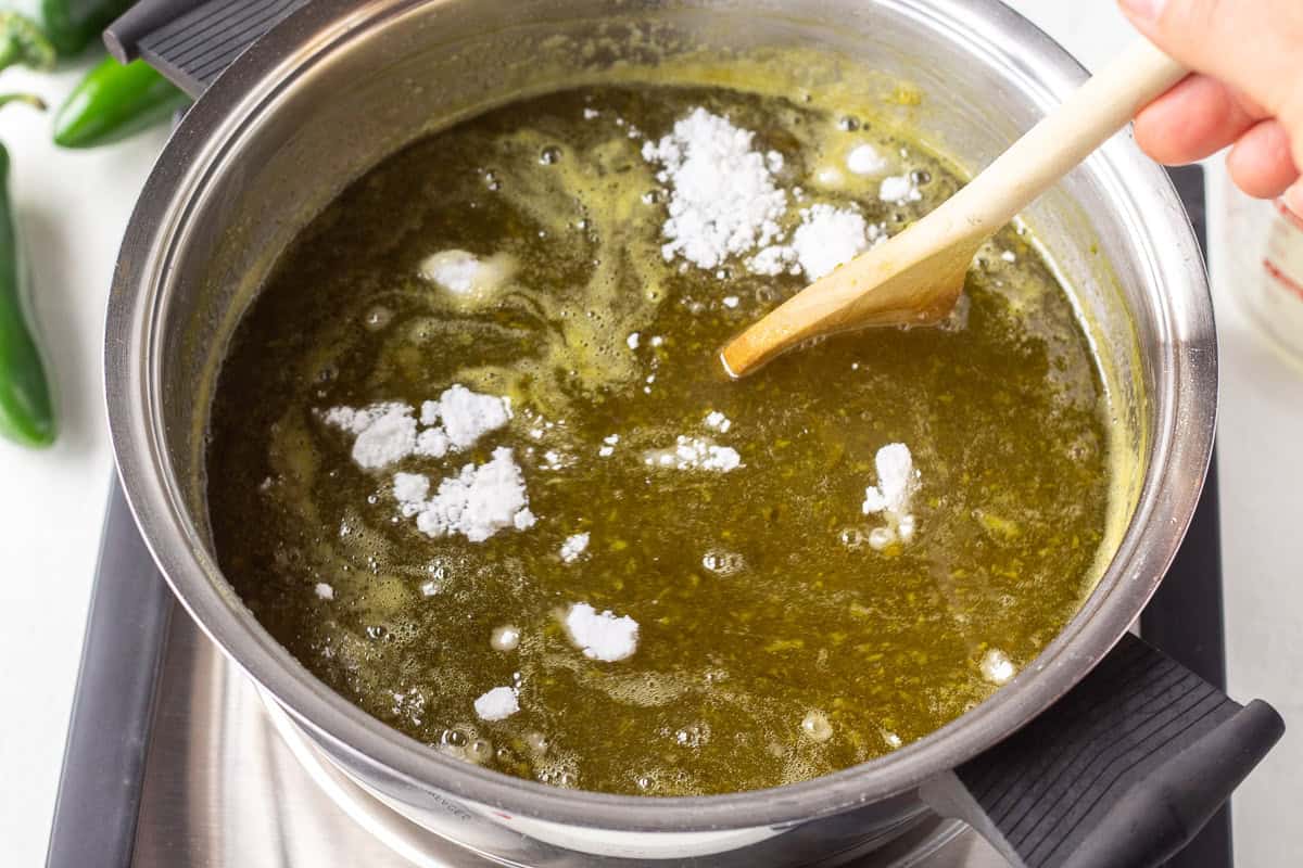 Cooking green pepper jelly in a saucepan with sugar and pectin.