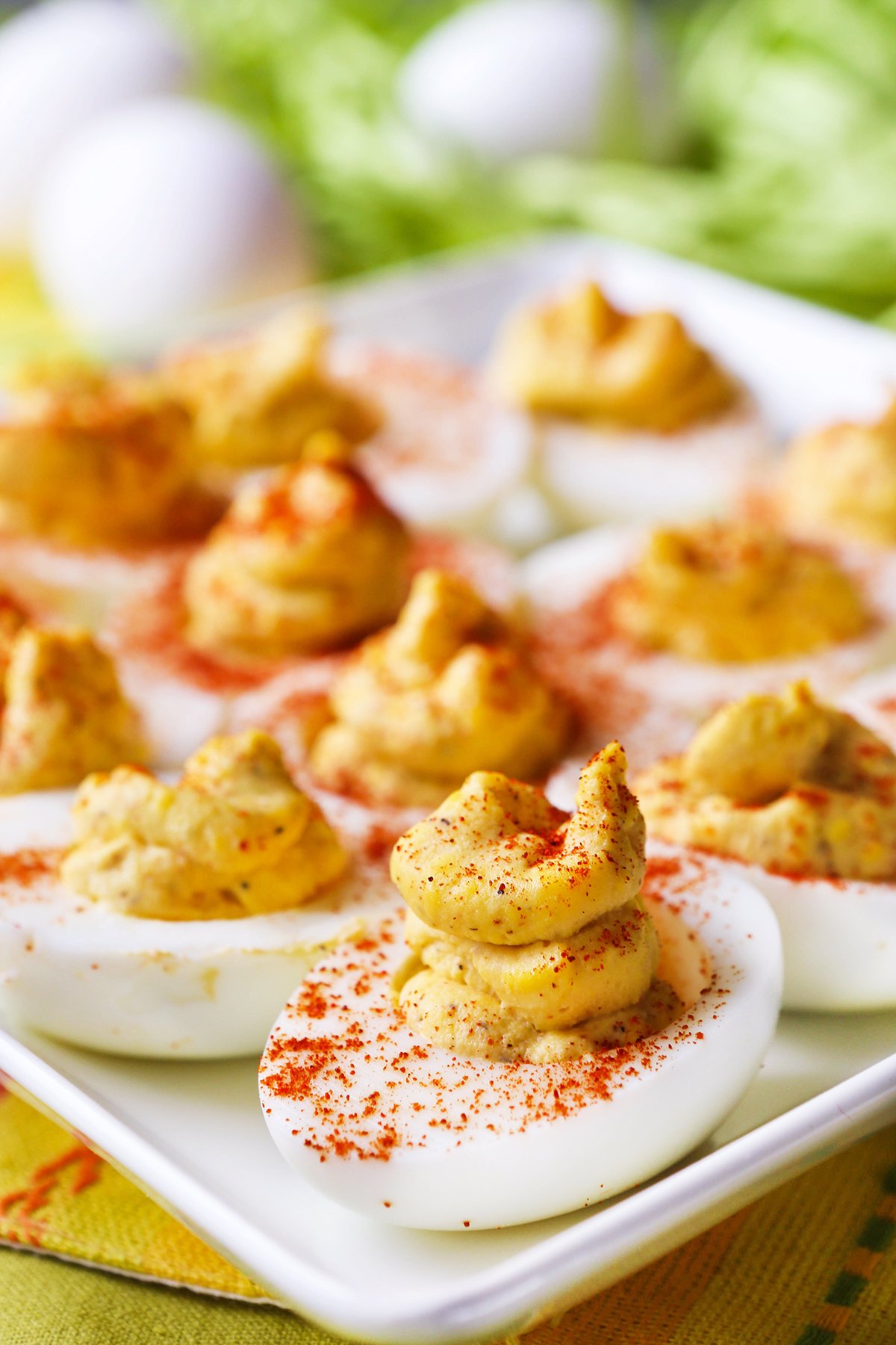 Deviled eggs lined up on a serving plate in a single row, with paprika sprinkled over the tops.