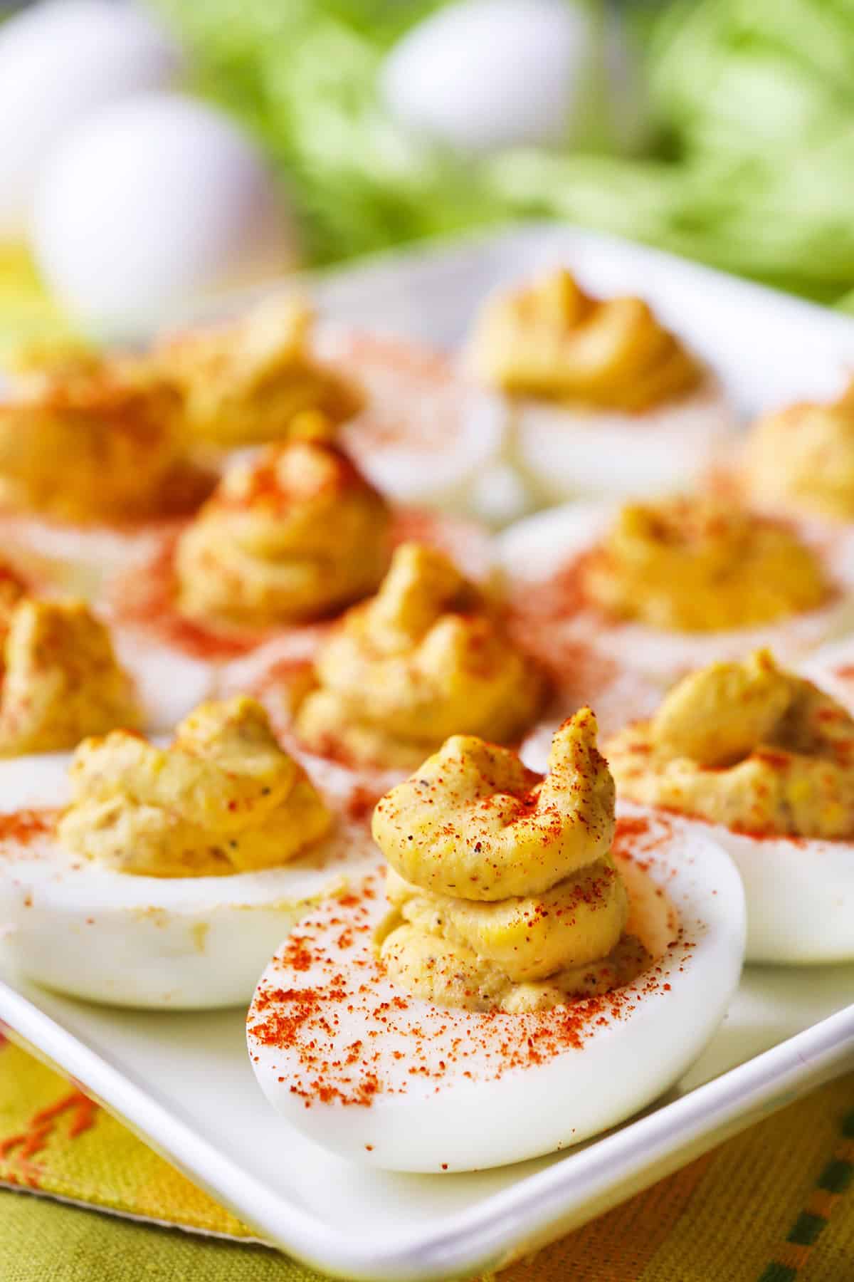 Deviled eggs lined up on a serving plate in a single row, with paprika sprinkled over the tops.