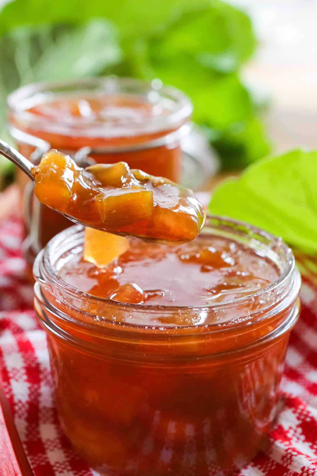 Spoon lifting apricot preserves out of a mason jar.