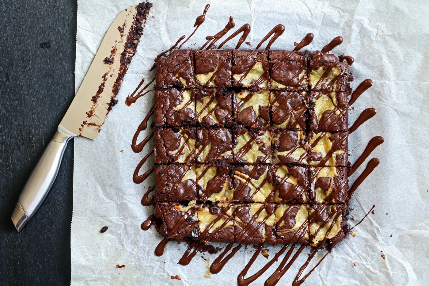 Fudgy chocolate brownie with lemon curd on parchment paper and cut into small squares. 