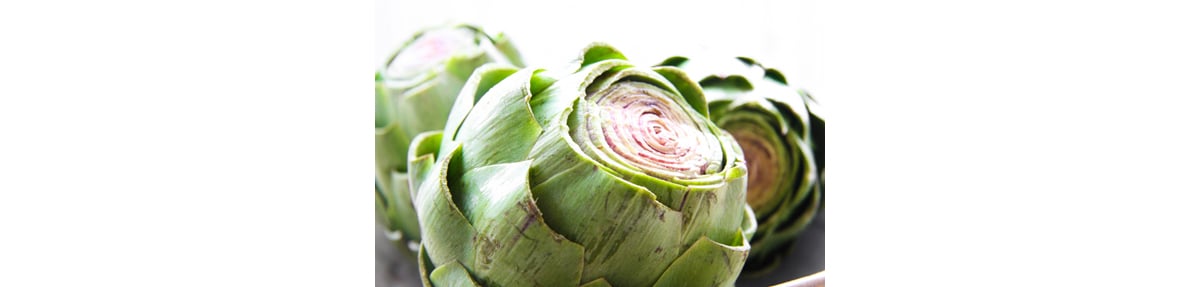 Fresh whole artichokes with tops of leaves cut off.