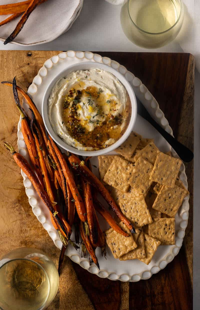 Whipped goat cheese with honey served in a bowl and crackers on the side. 