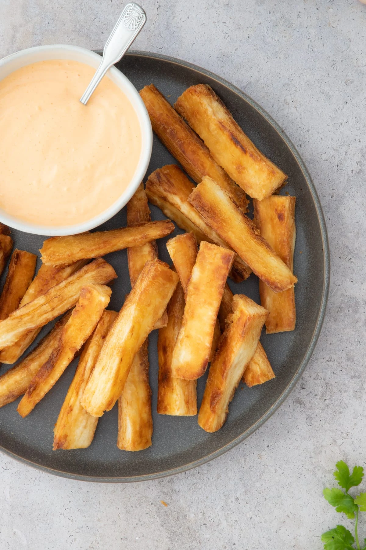 Yuca fries on a plate with a side of dipping sauce. 