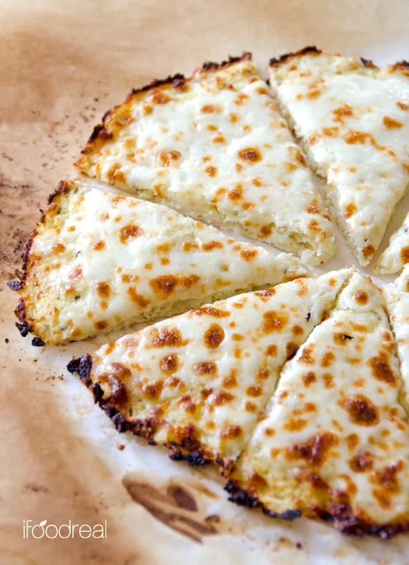 Cheese topped cauliflower pizza crust cut into triangle pieces. 