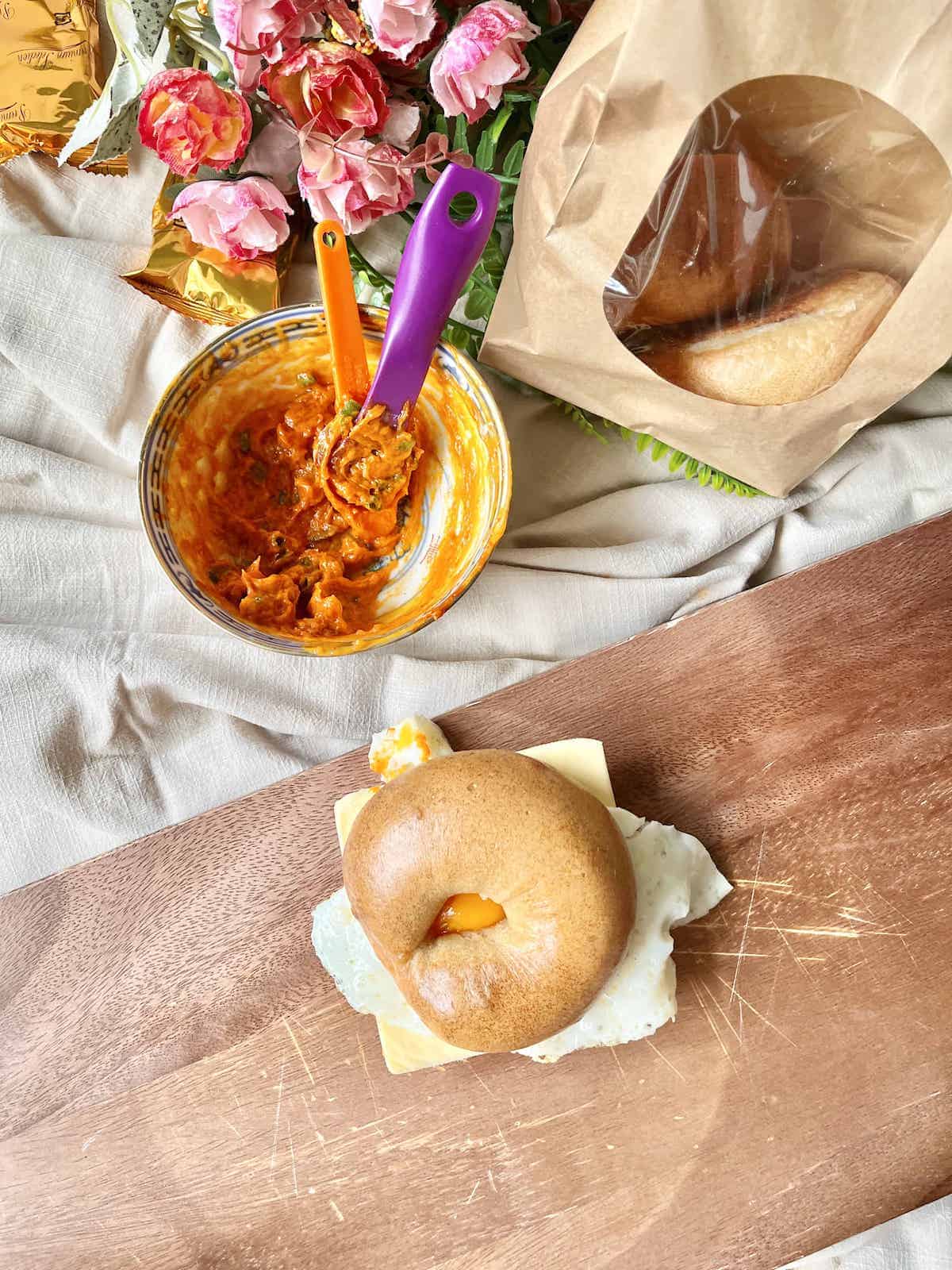 Gochujang butter in a small bowl next to a bagel topped with it. 