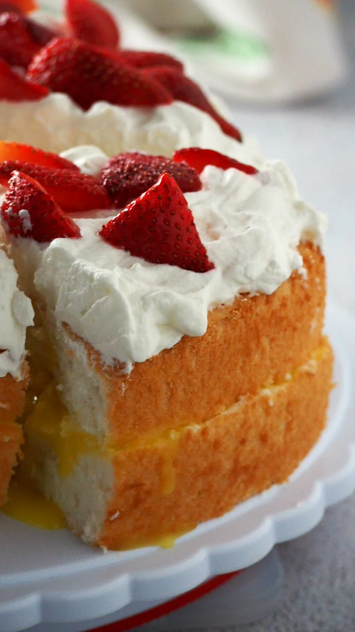 Lemon angel food cake layered with lemon curd and whipped cream with fresh strawberries on top. 
