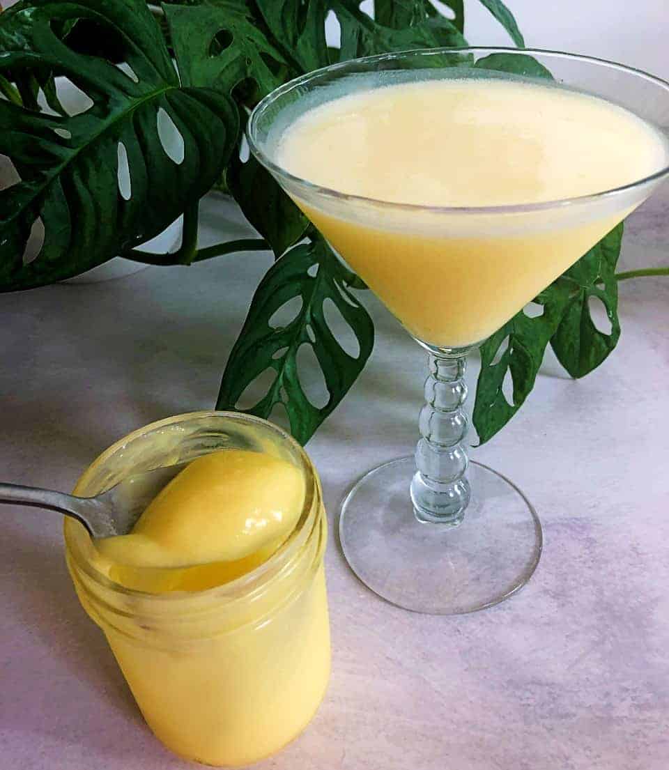 Glass jar of lemon curd next to to a lemon cocktail. 