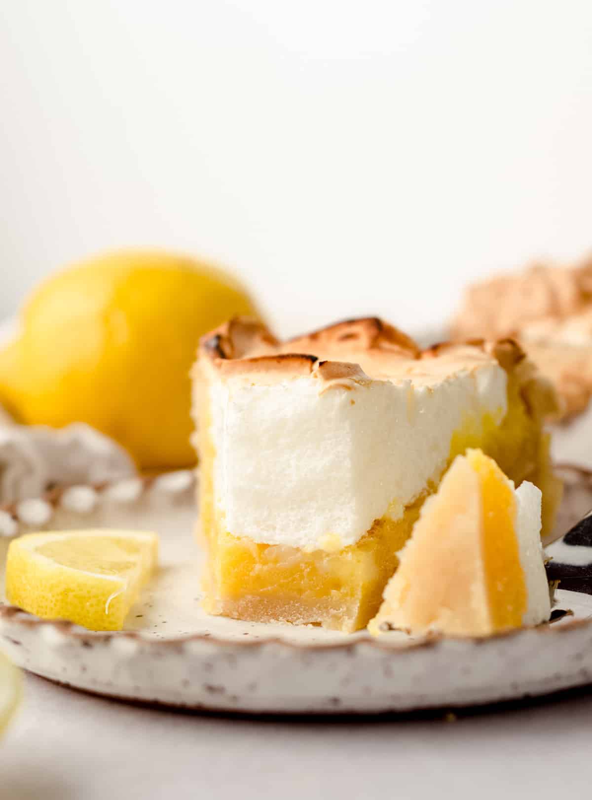 Slice of lemon meringue pie and a bite removed. 