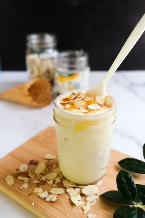 Spoon sticking out of lemon curd frozen dessert in a glass. 