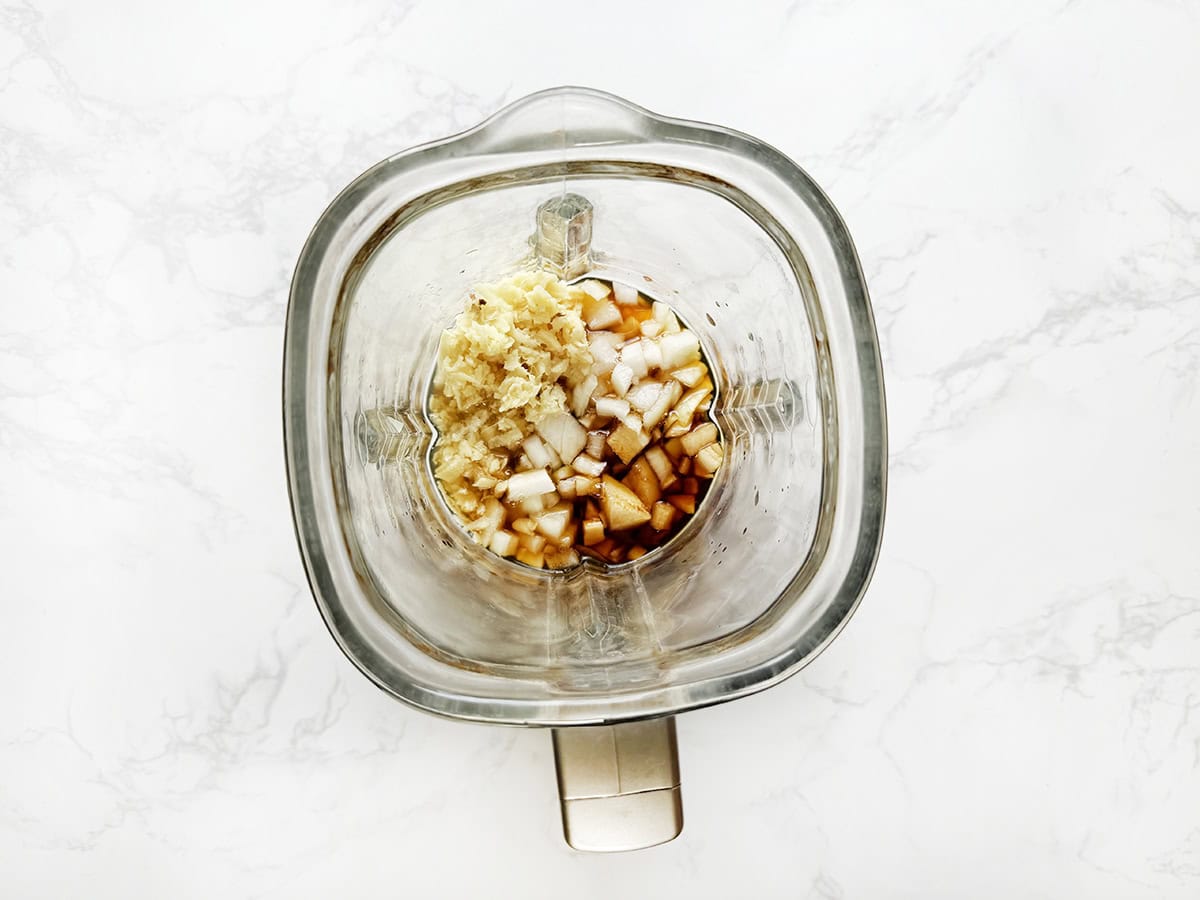 Blender with garlic, onions, and seasonings for cooking or food preparation.