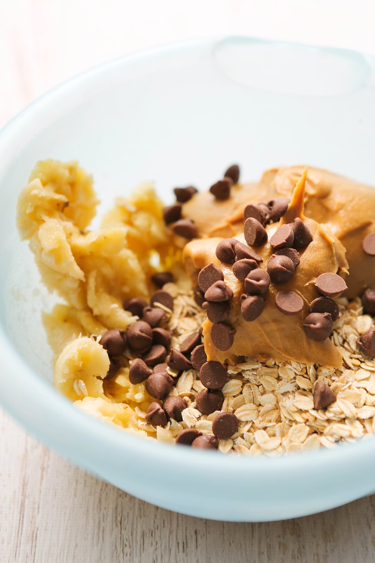 Mixing bowl with oats, peanut butter, mashed banana and chocolate chips.