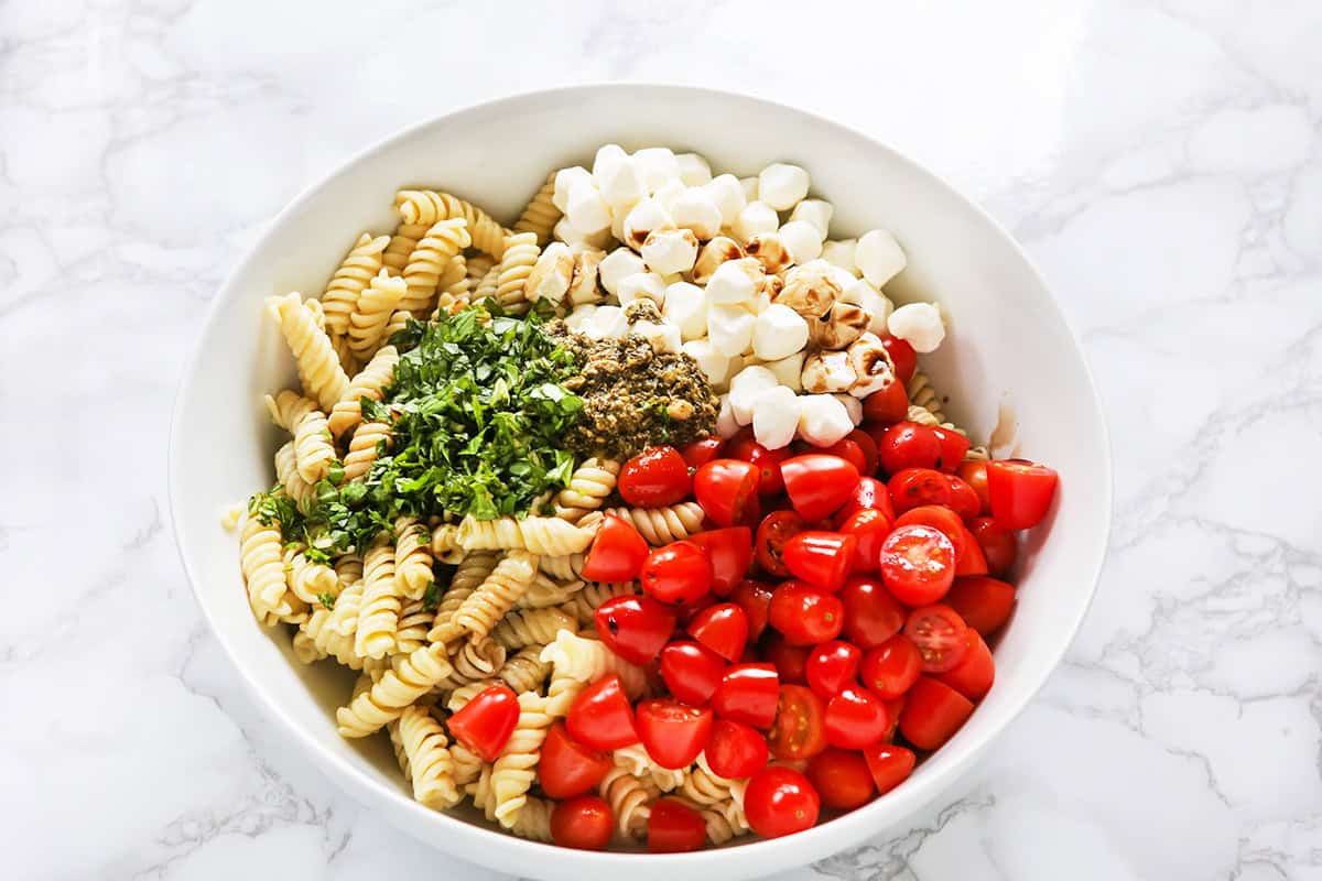 Pesto Caprese Pasta Salad with cherry tomatoes, mozzarella, and basil.