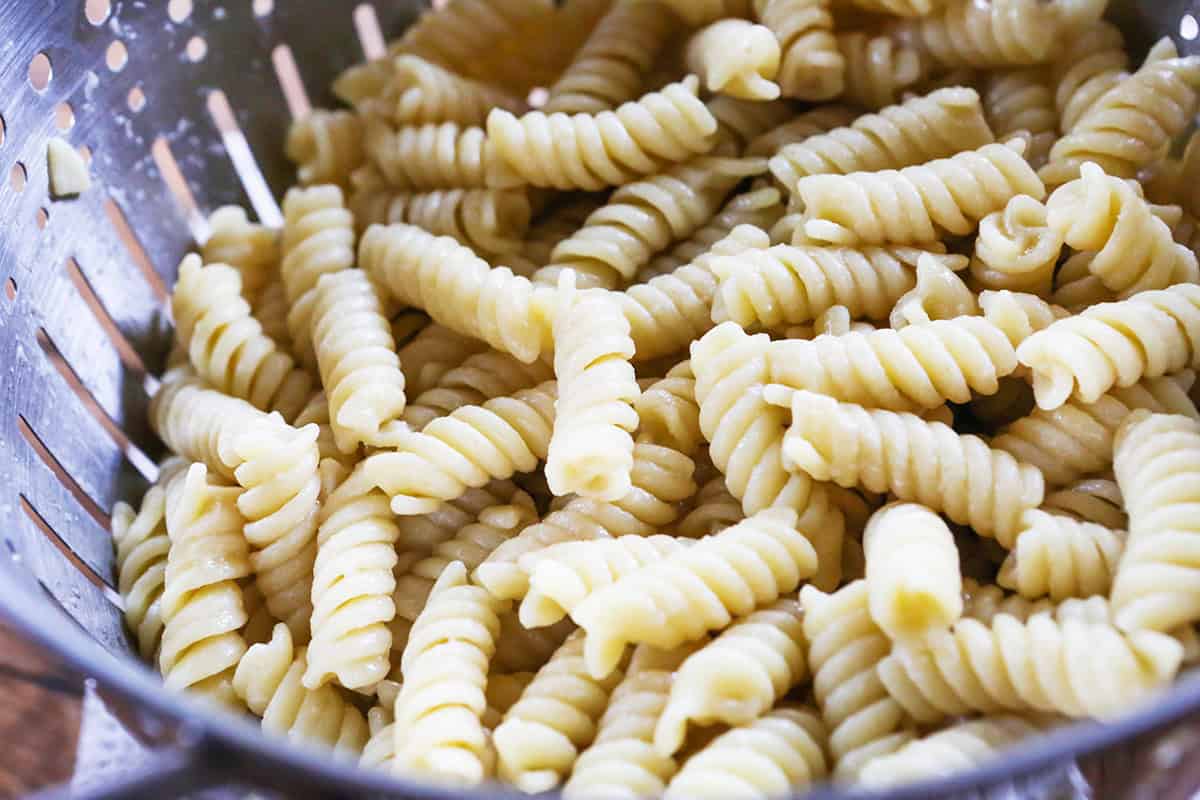 Cooked rotini pasta in a colander, ready for salad preparation.