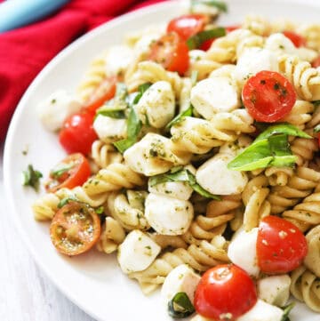 Colorful pesto caprese pasta salad with cherry tomatoes and mozzarella.