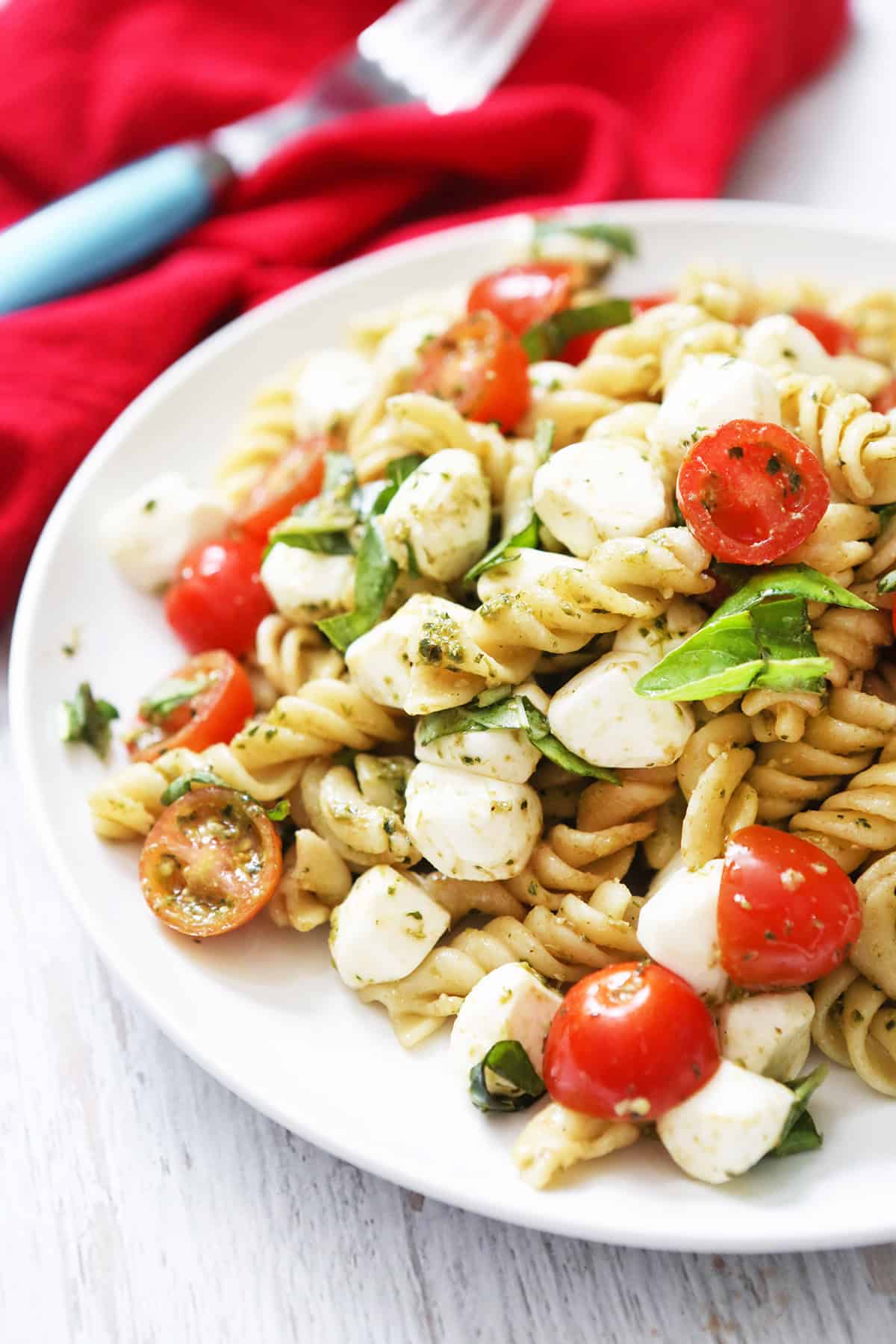 Colorful pesto caprese pasta salad with cherry tomatoes and mozzarella.