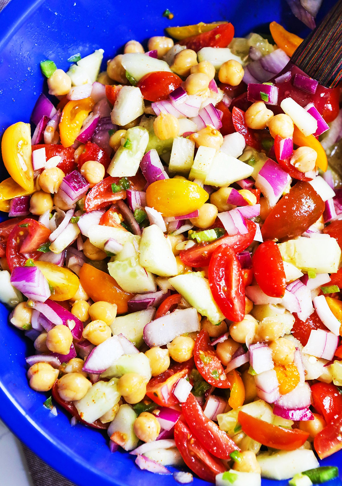 Close up photo of a veggie salad in a mixing bowl with chickpeas.