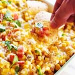 Cream cheese corn dip with herbs and tortilla chips for snacking.