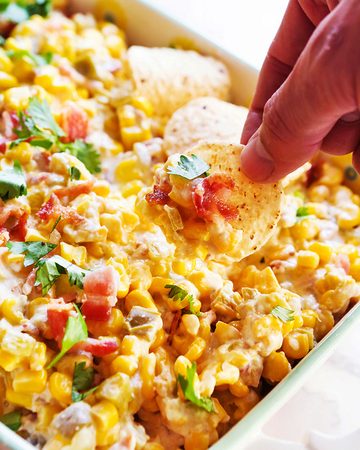 Cream cheese corn dip with herbs and tortilla chips for snacking.