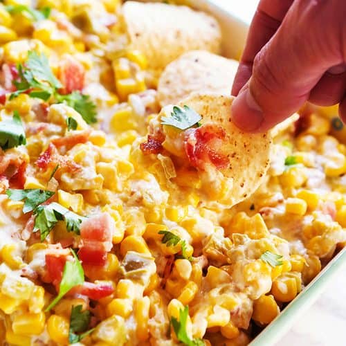 Cream cheese corn dip with herbs and tortilla chips for snacking.