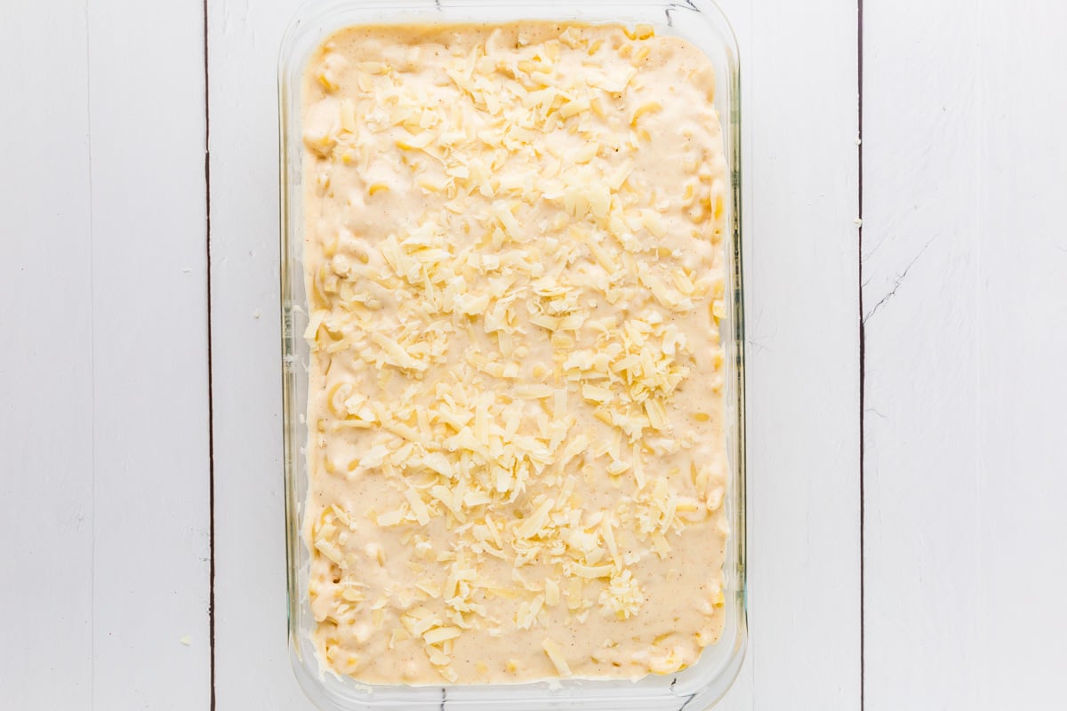 Mac and cheese in a baking dish with creamy white sauce, and topped with shaved Parmesan cheese.