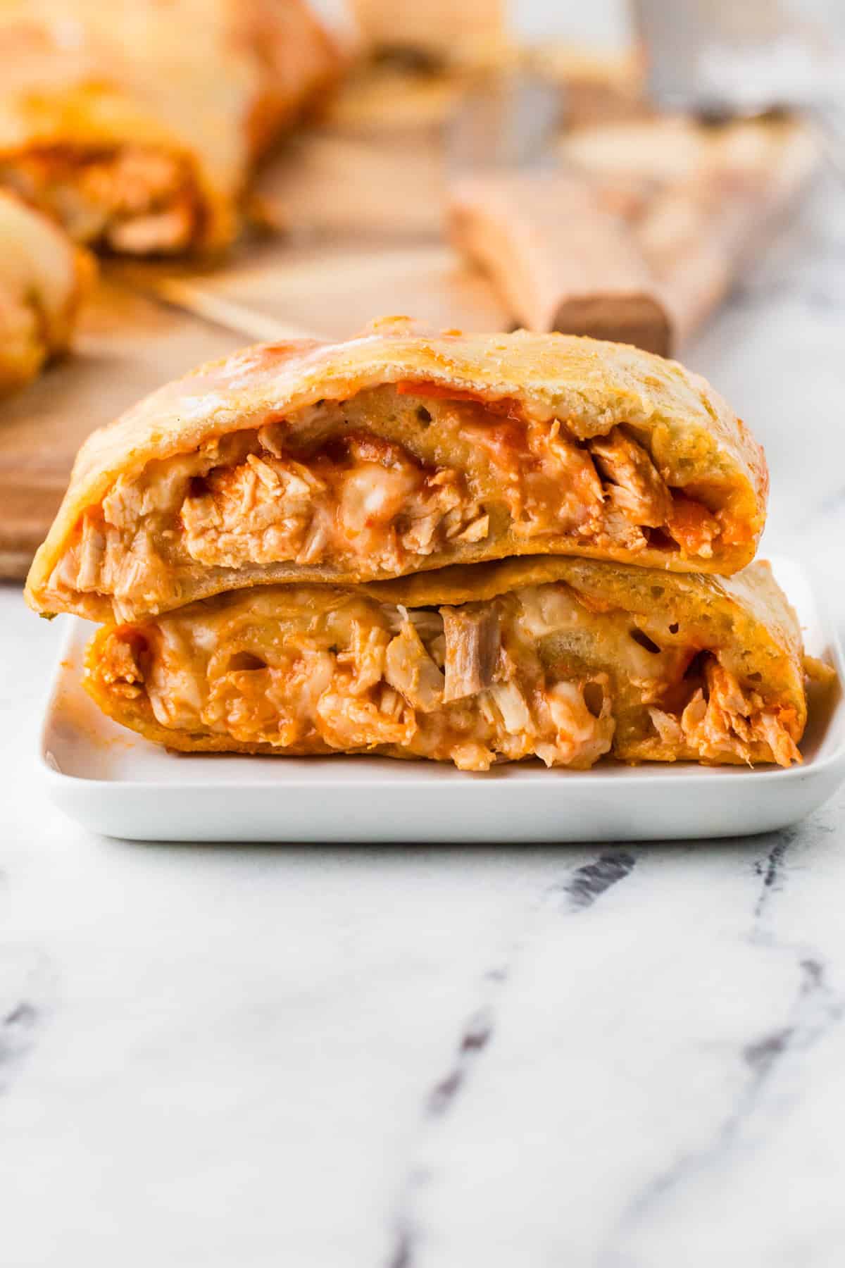 Two pieces of stromboli stacked, sitting on a white plate.