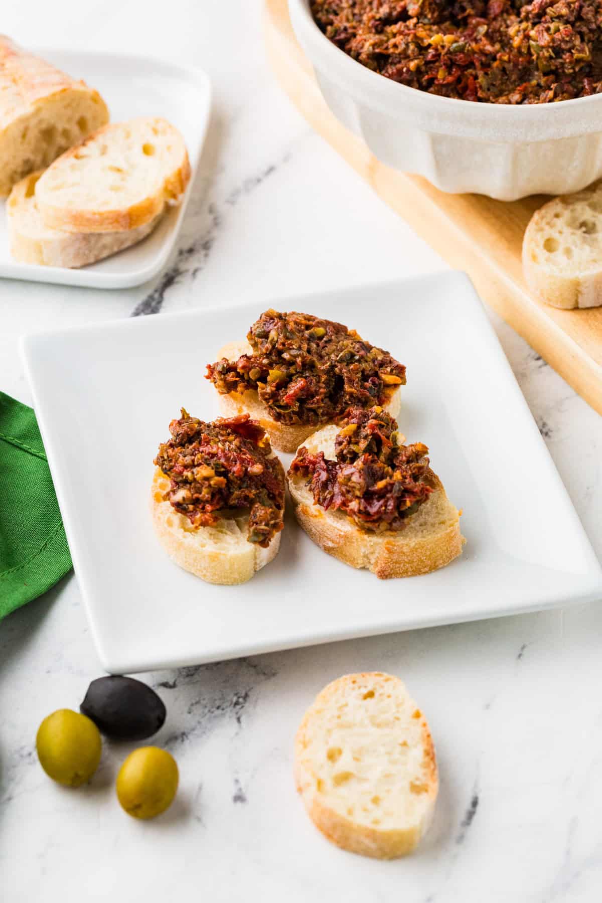 Three pieces of bruschetta with tapenade on a serving plate.