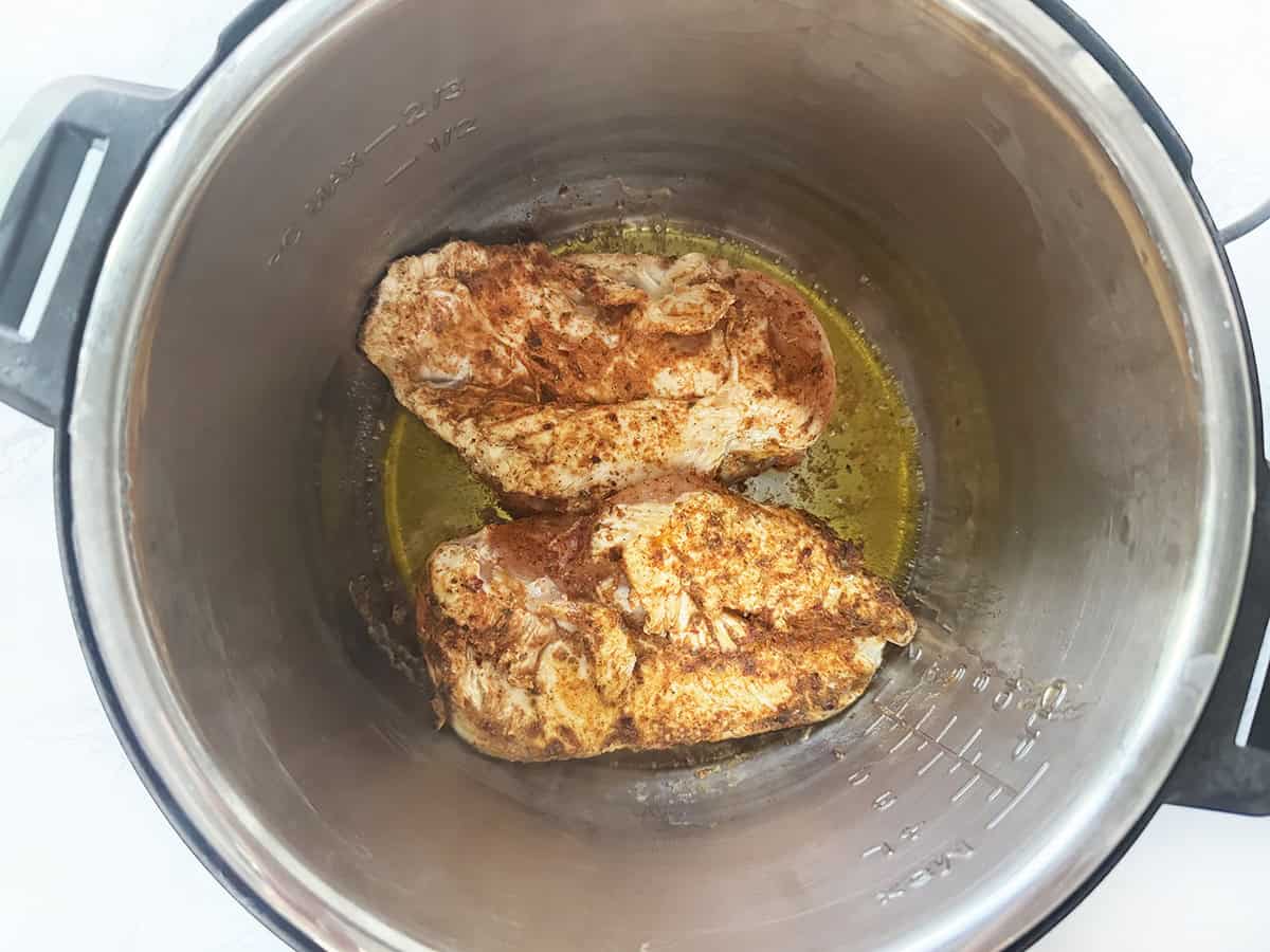 Juicy and crispy chicken thighs cooking in an Instant Pot with seasoned oil.