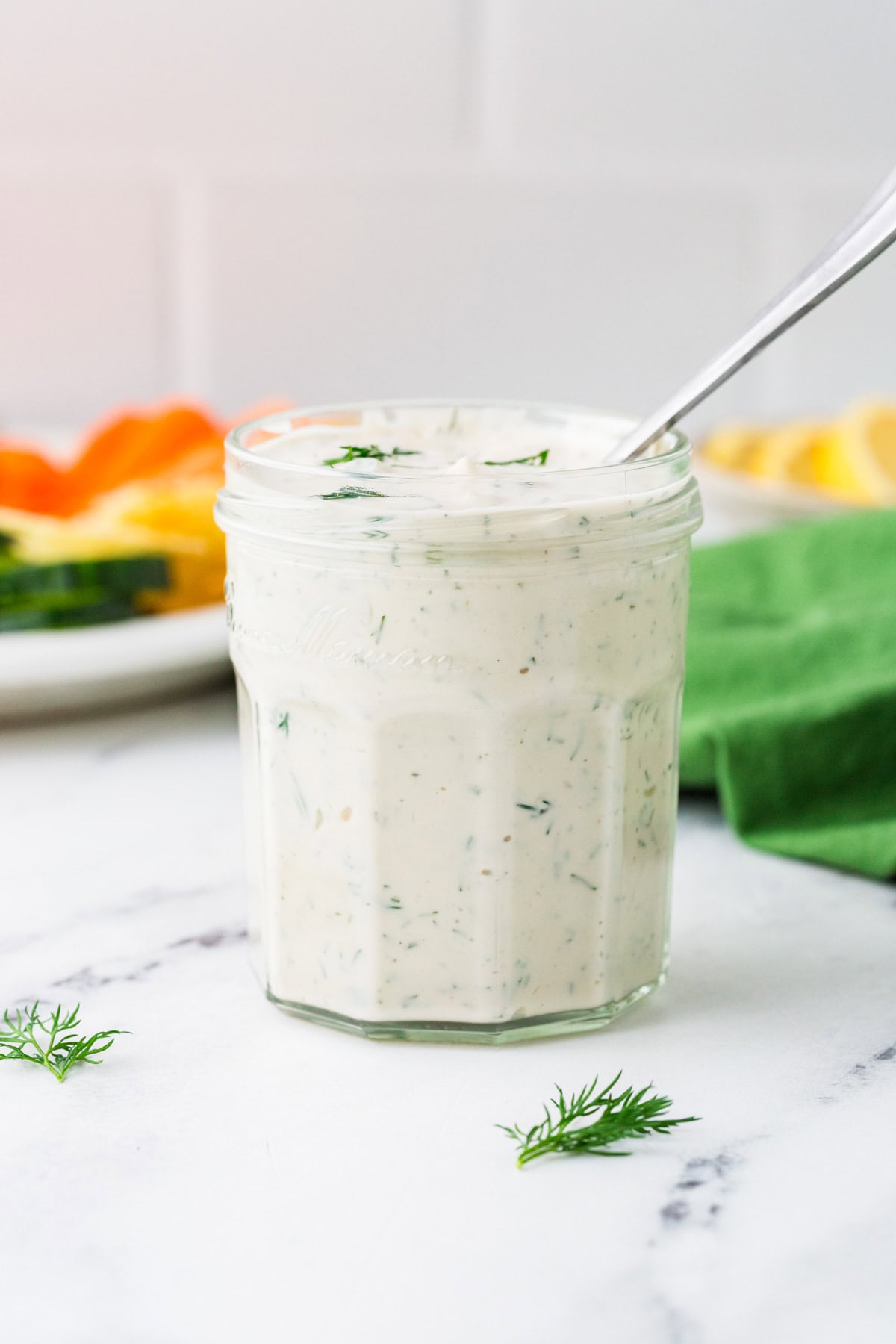 Jar of creamy dill dressing with a spoon inside.