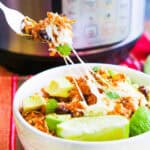 Delicious burrito bowl with avocado, black beans, and cilantro in a white bowl.