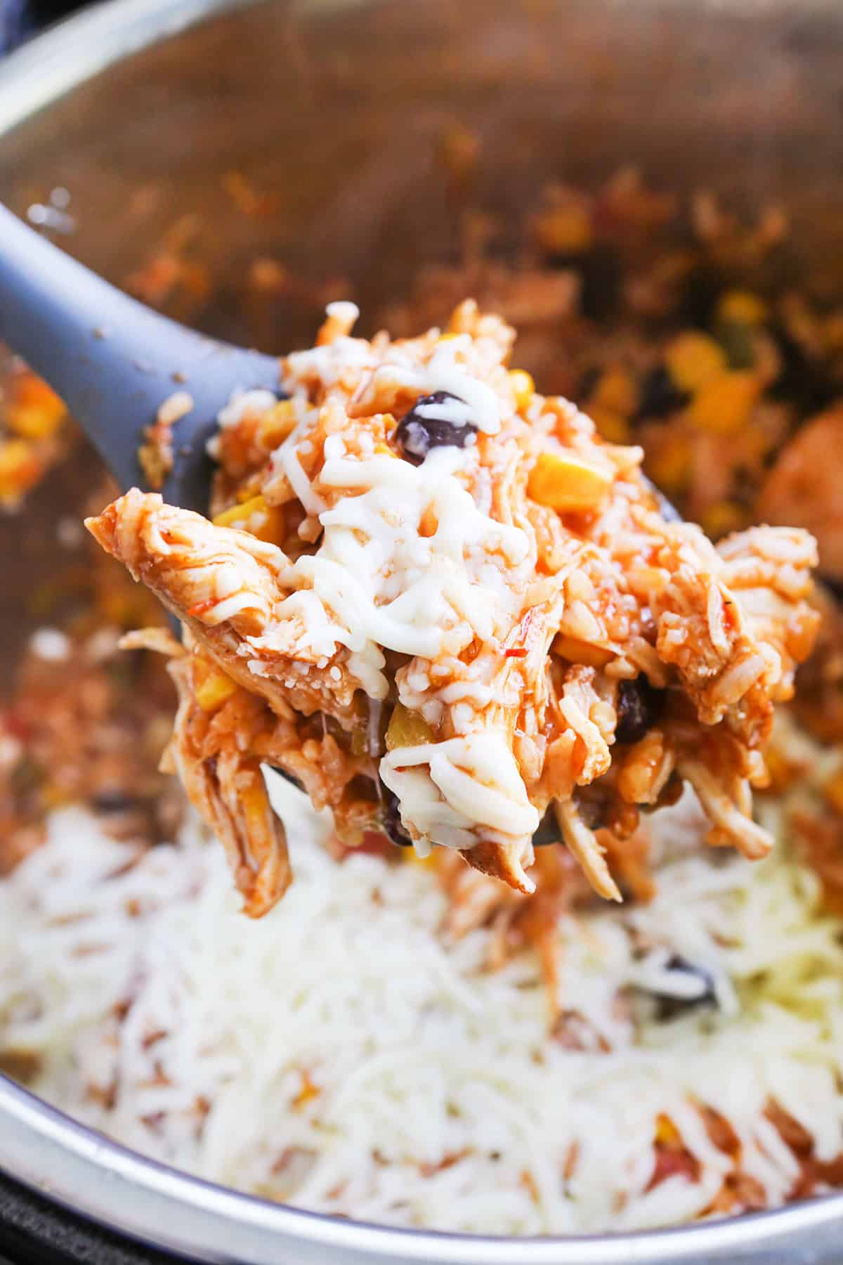 Cheesy chicken and rice casserole with shredded cheese and cooked chicken in a pot.