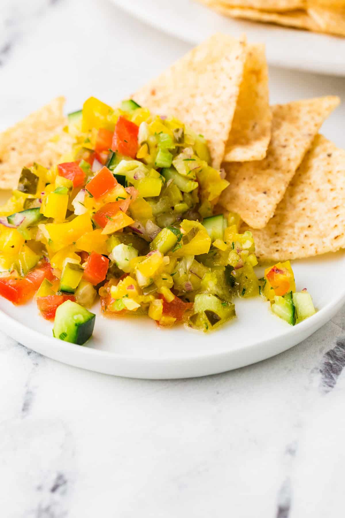 Plate of pickle de gallo with a few chips next to the pile.
