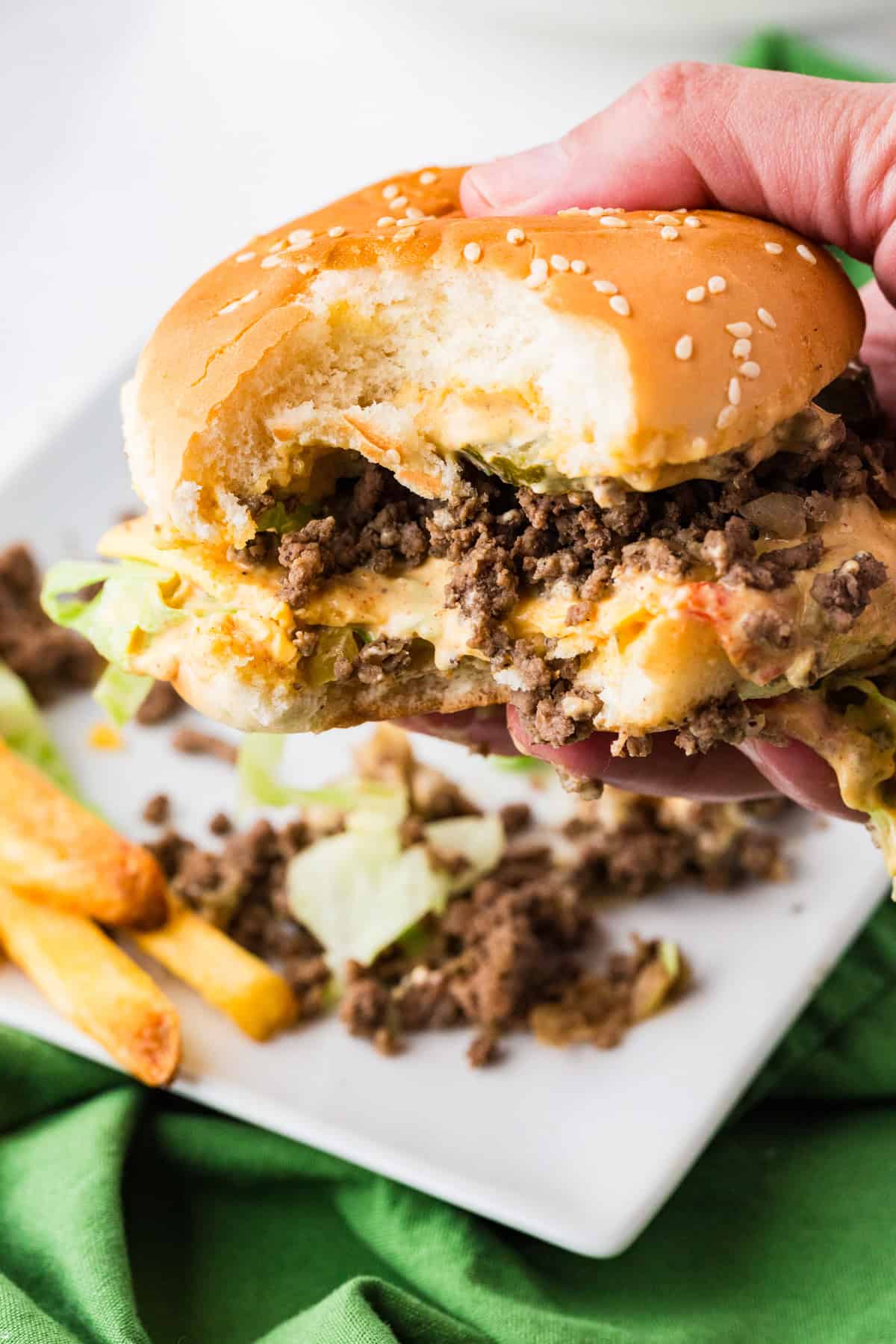 Hand holding up a big mac sloppy joe with a few bites taken out.