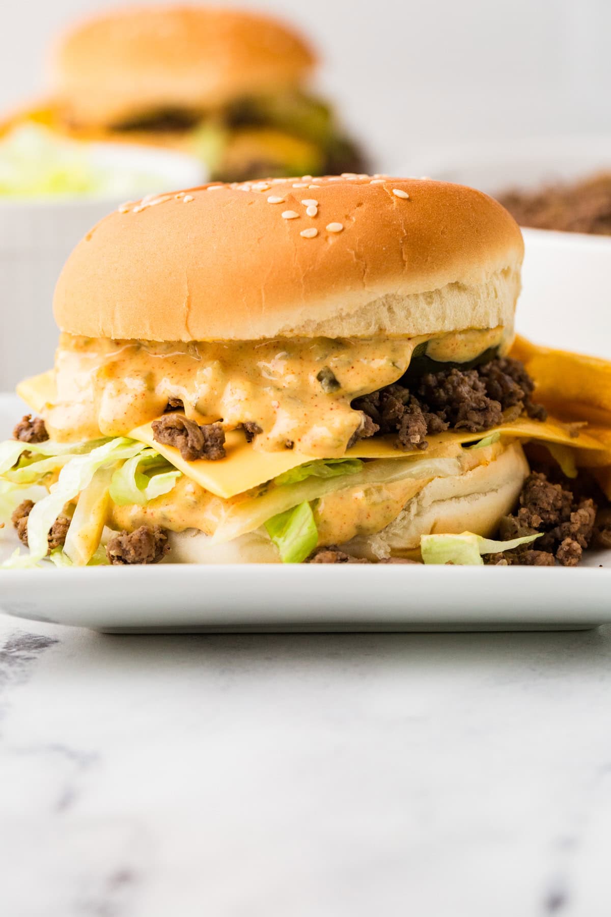 Close up side view of a sloppy joe with big mac sauce drizzling down the sides.