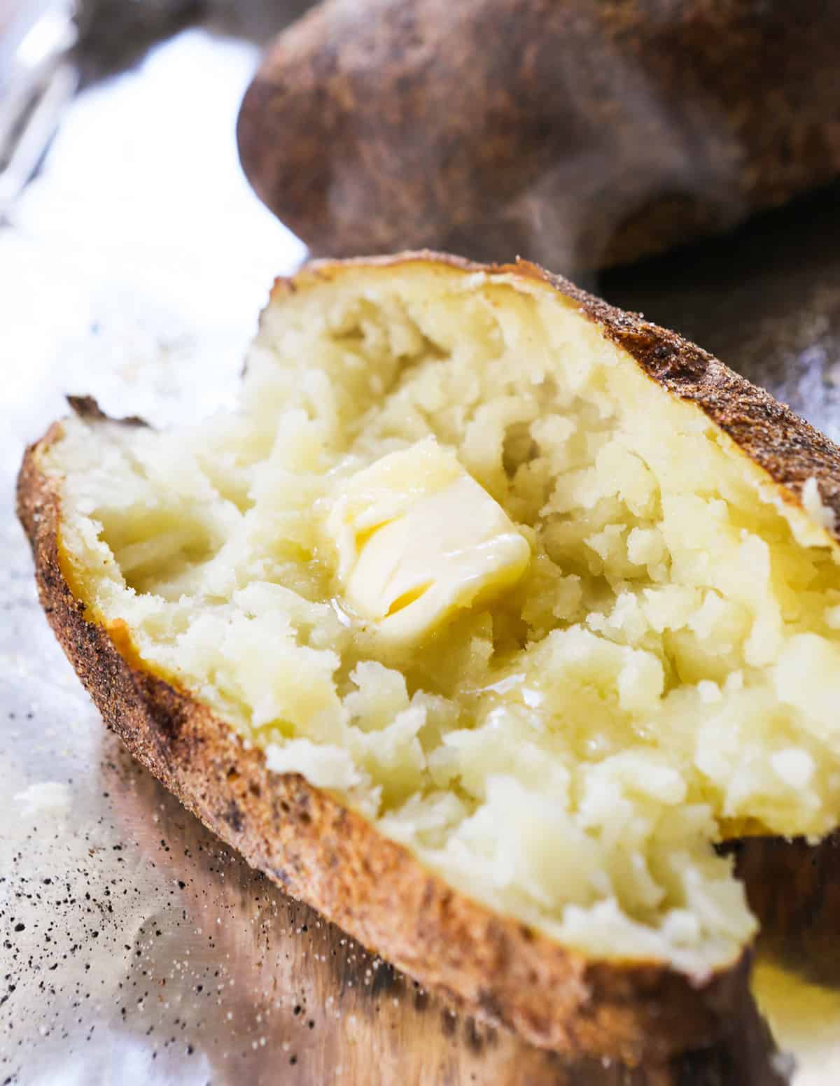 Close-up of baked potato with butter and crispy skin.