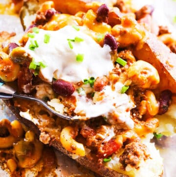 Baked potato topped with chili, cheese, sour cream, and green onions.