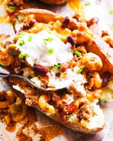 Baked potato topped with chili, cheese, sour cream, and green onions.