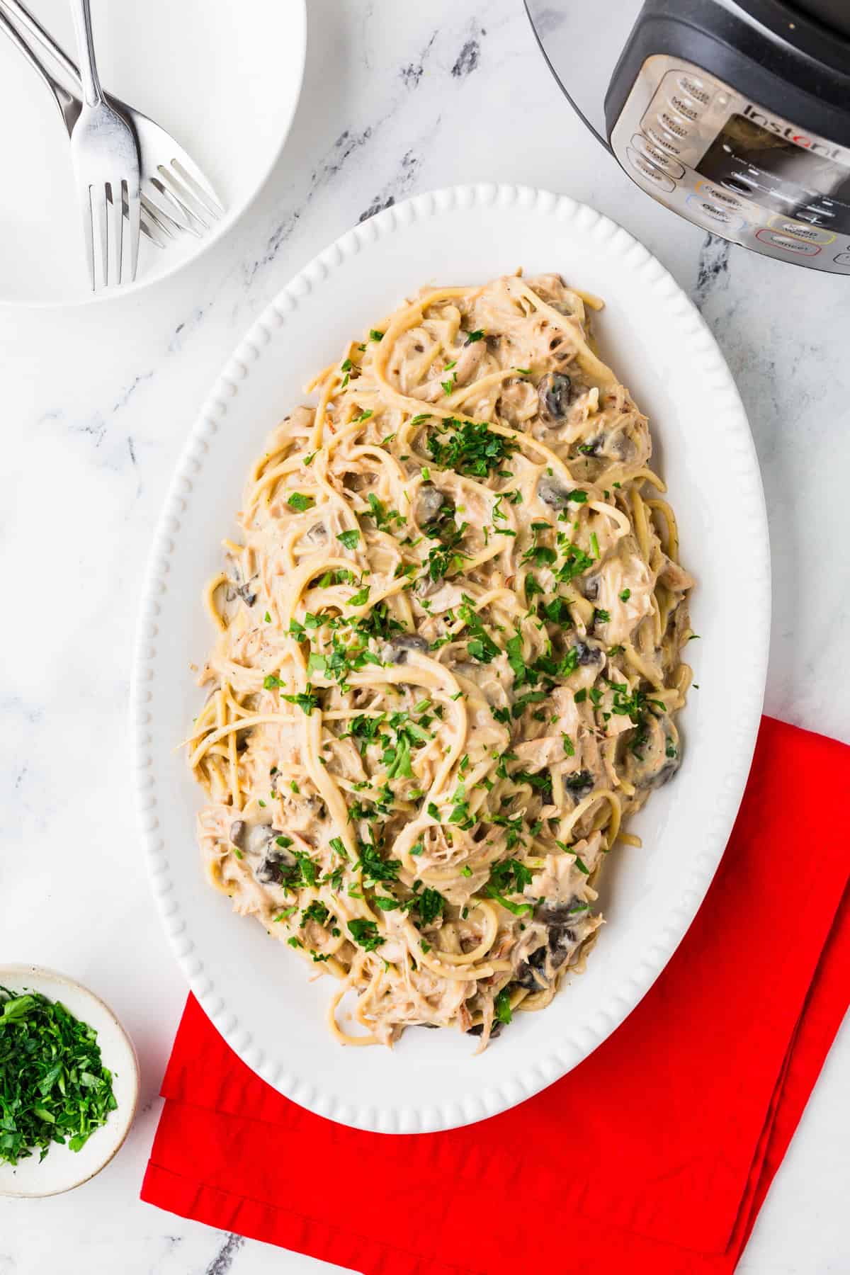 Top view of an oval-shaped serving dish filled with chicken tetrazzini and topped with fresh parsley.