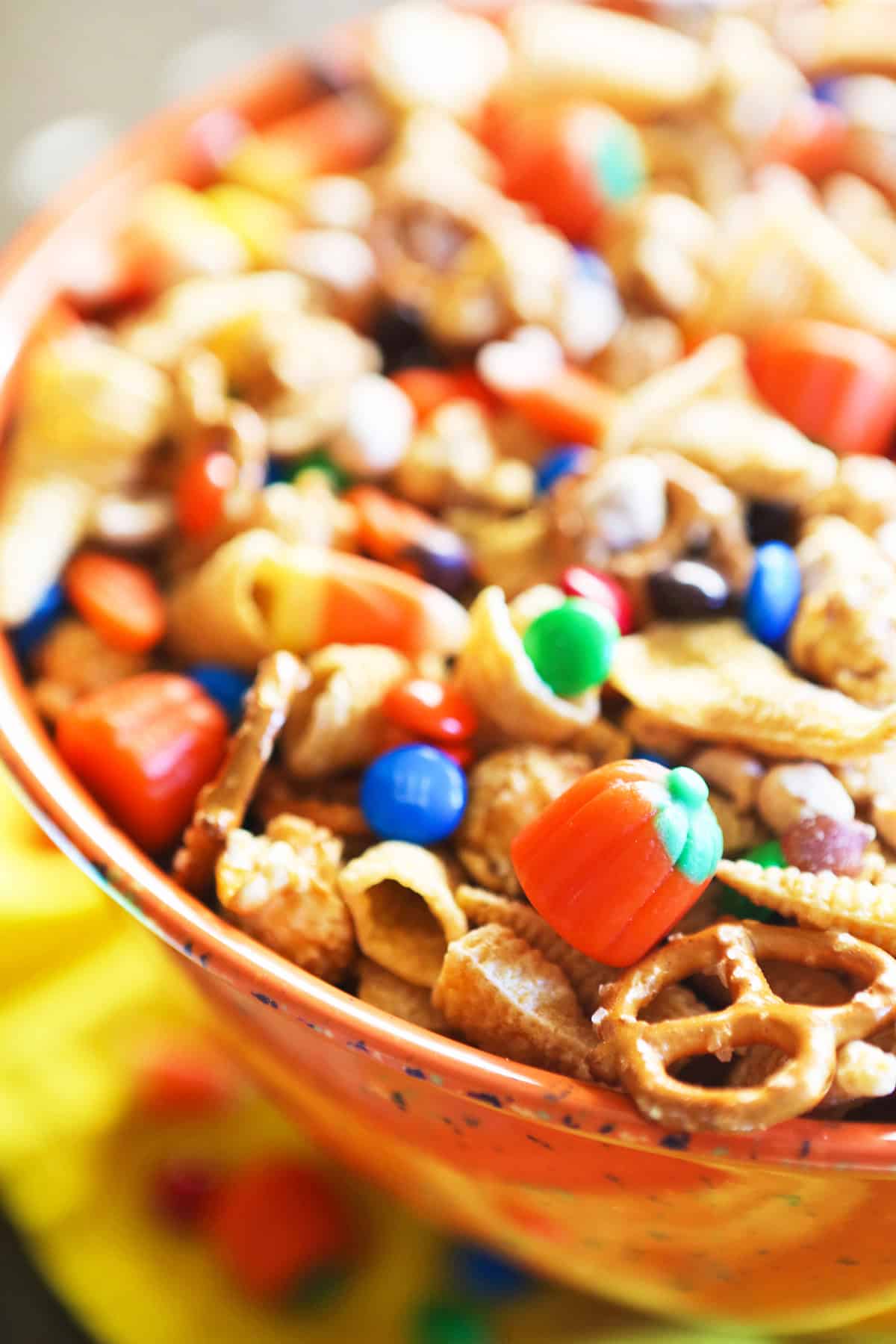Colorful Halloween snack mix with candy, pretzels, and chocolate pieces in a bowl.