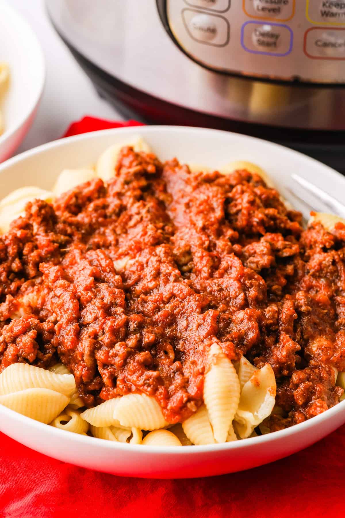 Bowl of cooked pasta shells covered with a saucy ground beef mixture.