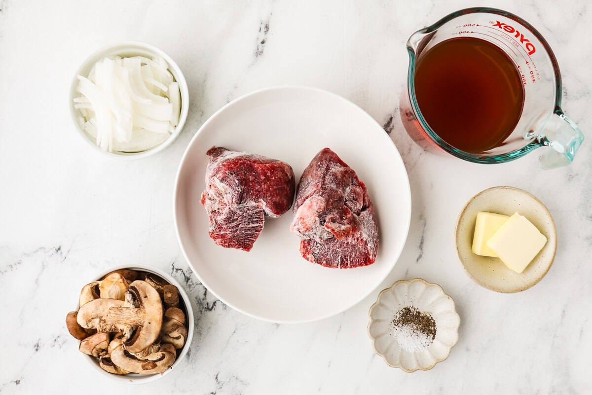 Ingredients needed to make Instant Pot frozen steak in individual bowls on a white counter.