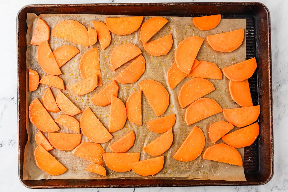 Baking tray filled with sliced sweet potatoes, ready to cook.