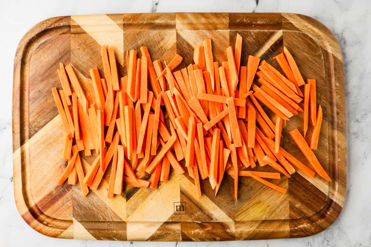 Sweet potato fries pre-cooked on a cutting board.