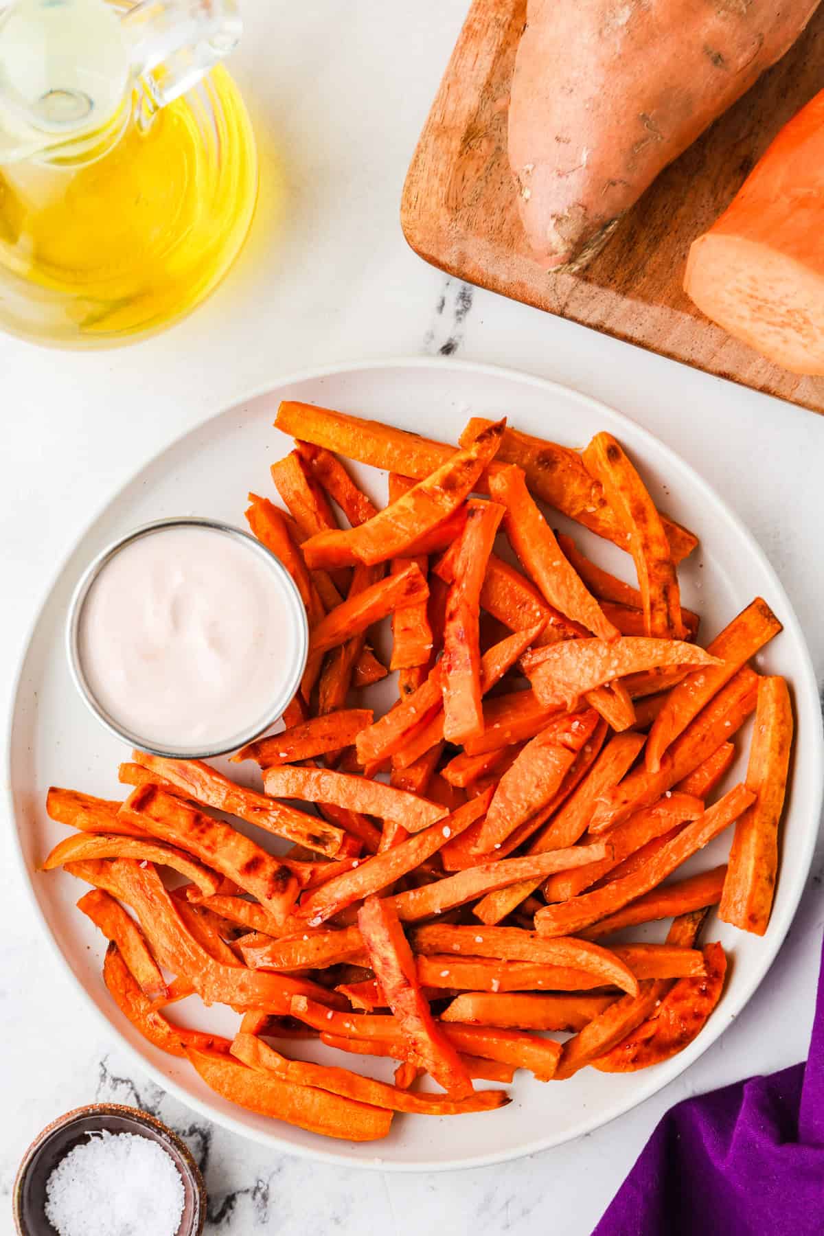 Top view of a platter filled with sweet potato fries surrounded by ingredients that made it.