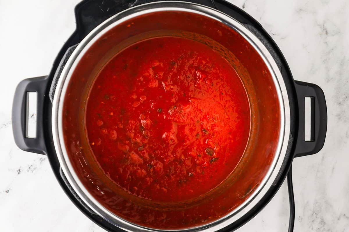 Slow cooker with tomato sauce ready for cooking.